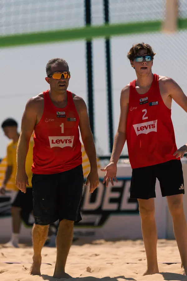 Two teammates in red Levi’s jerseys, numbers 1 and 2, walking the sand together