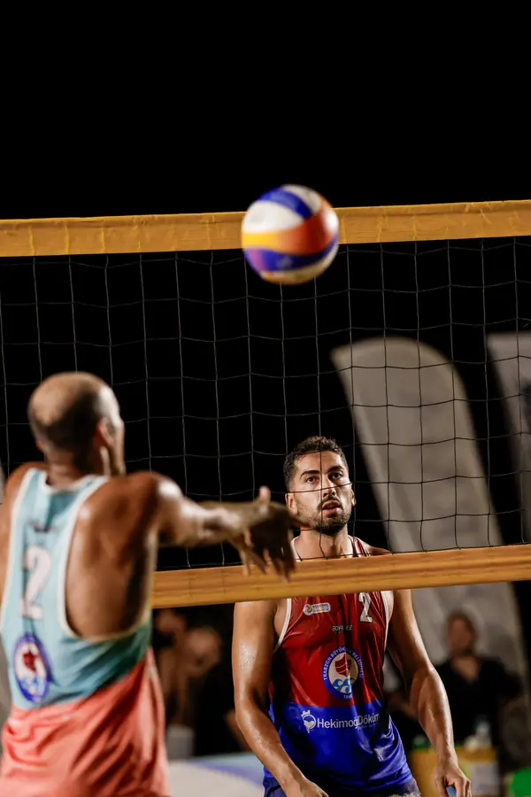 Attack at the net under night lights, ball in the air